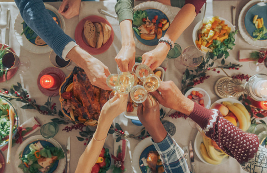 Van bovenaf zicht op een feestelijk gedekte wintertafel waar meerdere personen met glazen proosten.